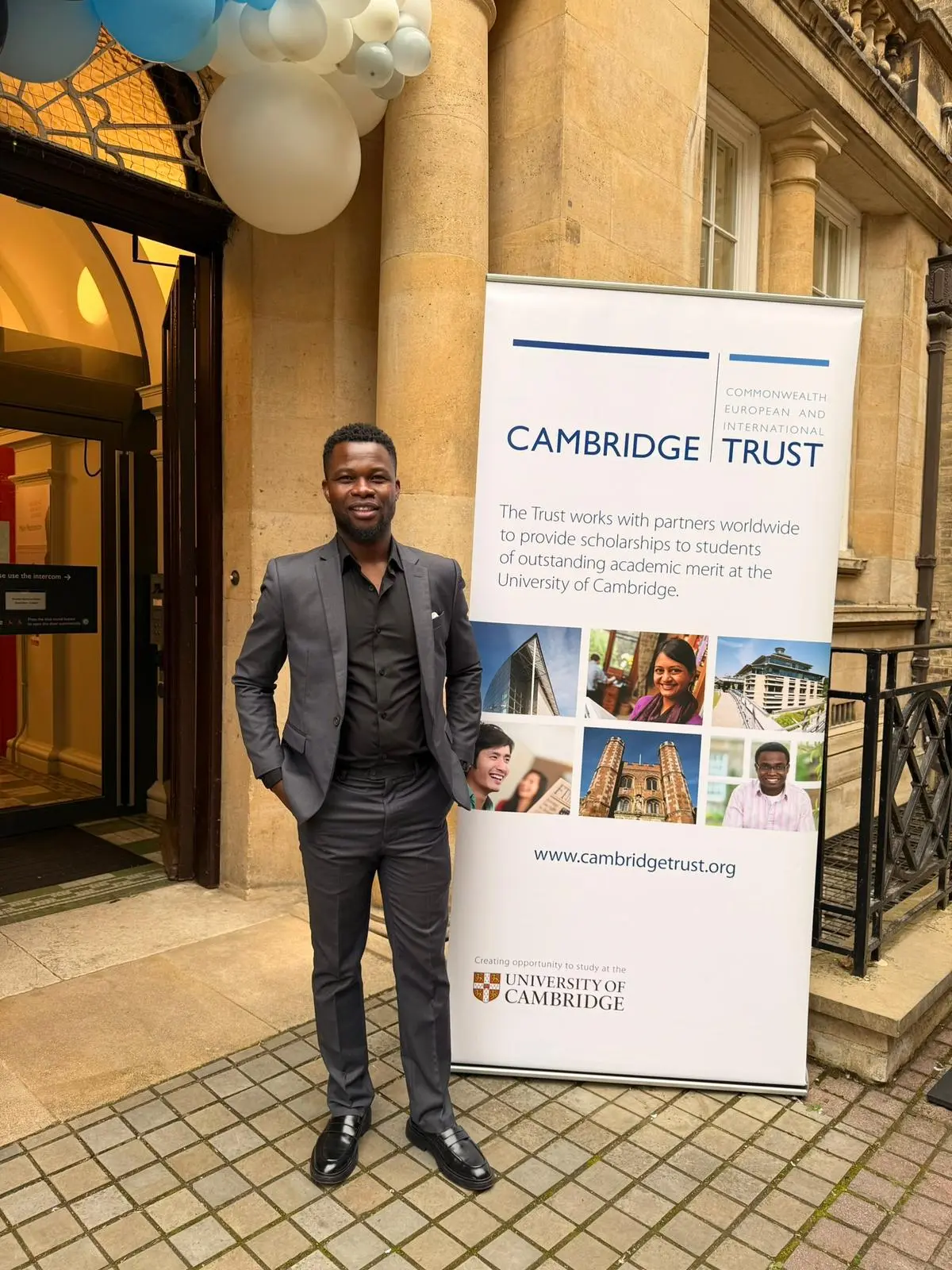 Abel Mavura standing in front of a Cambridge Trust banner