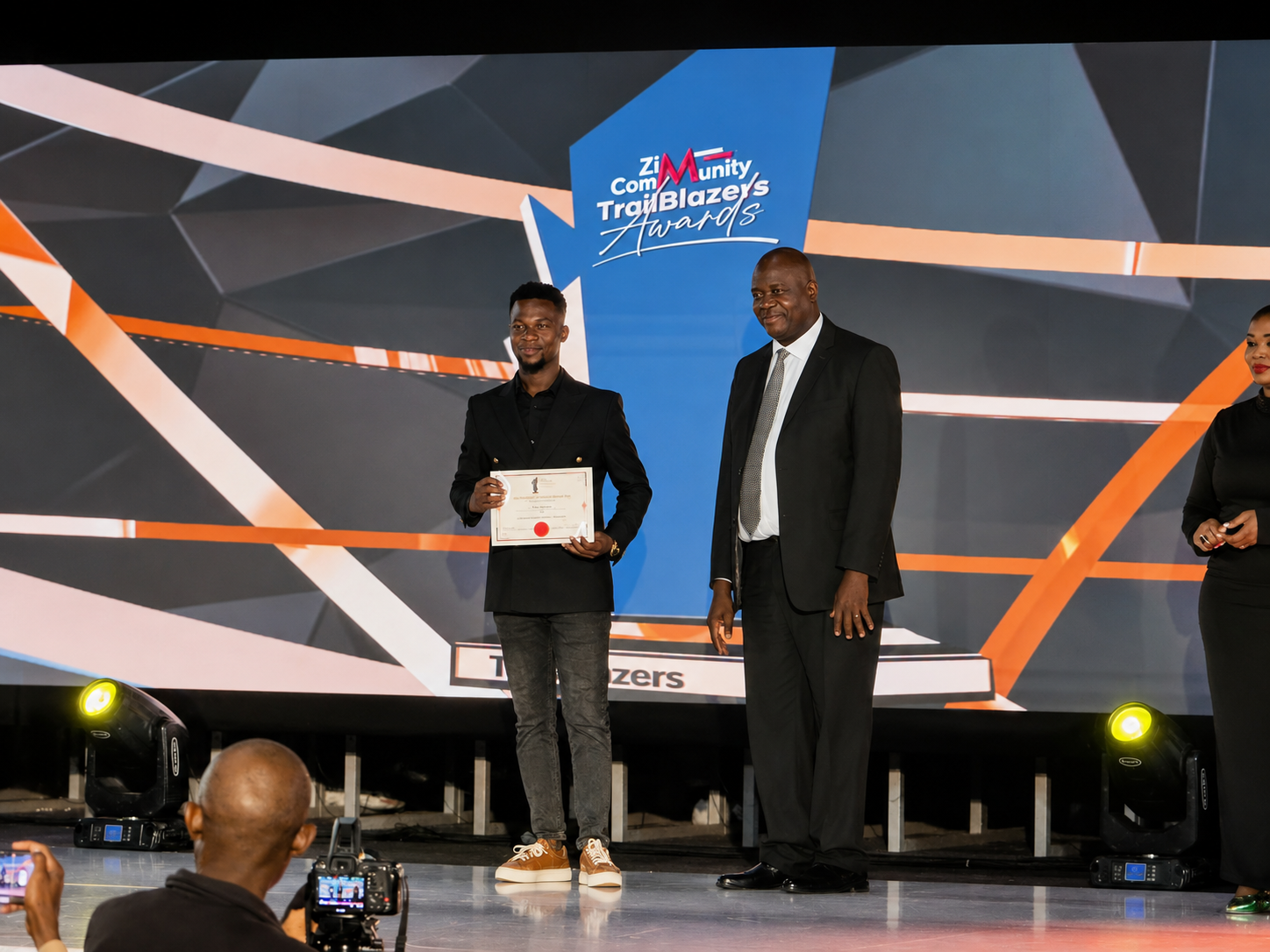 Abel Mavura receiving an award certificate on stage