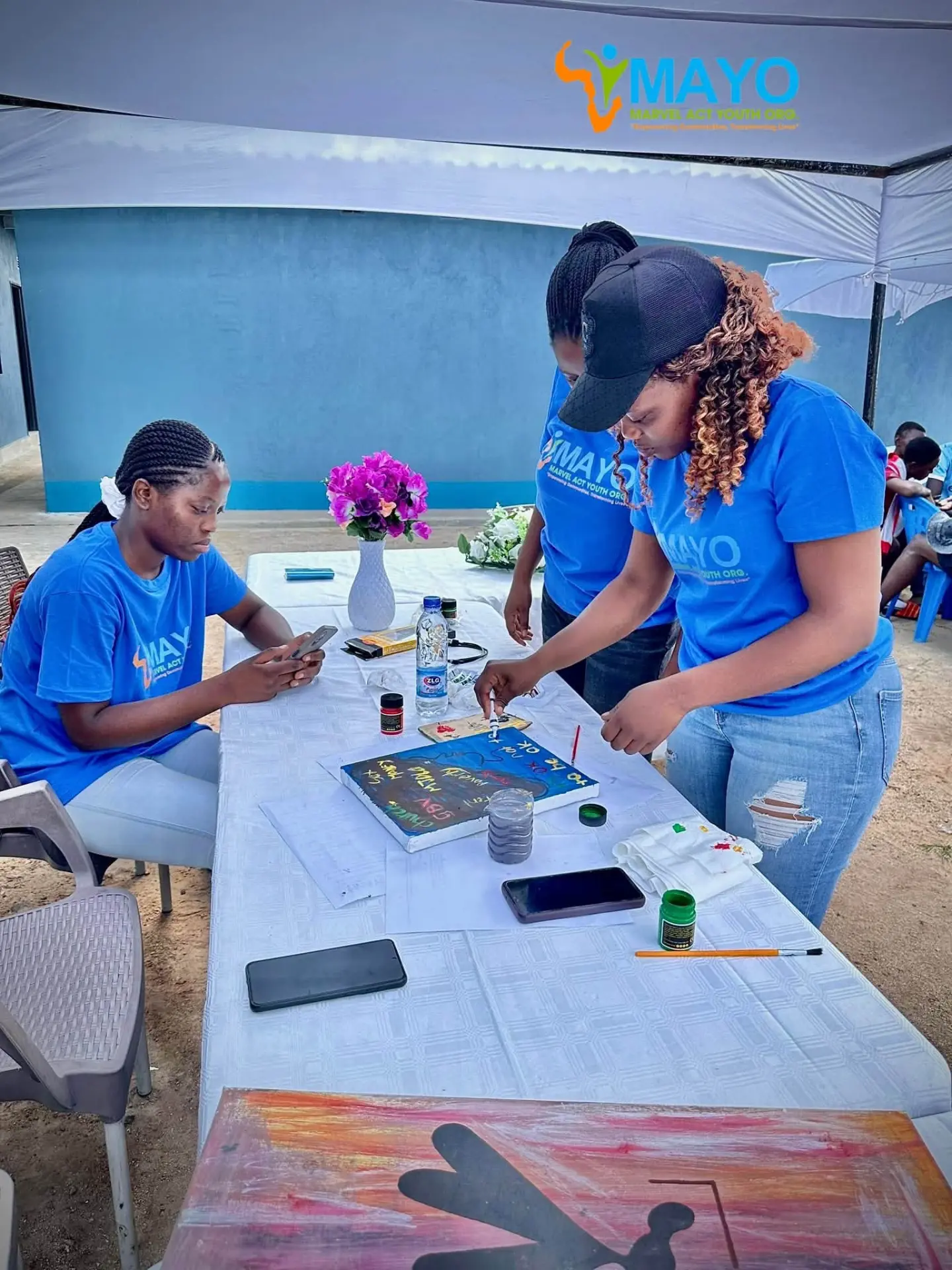 MAYO team members preparing awareness artwork under a tent