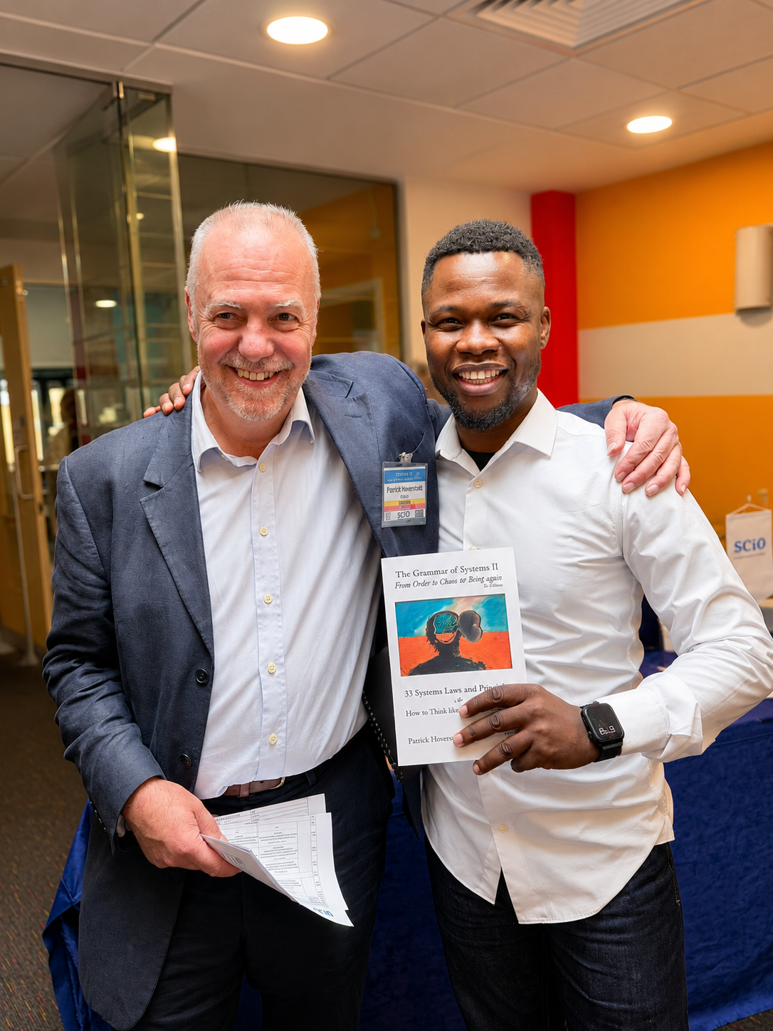 Abel Mavura holding a copy of The Grammar of Systems II