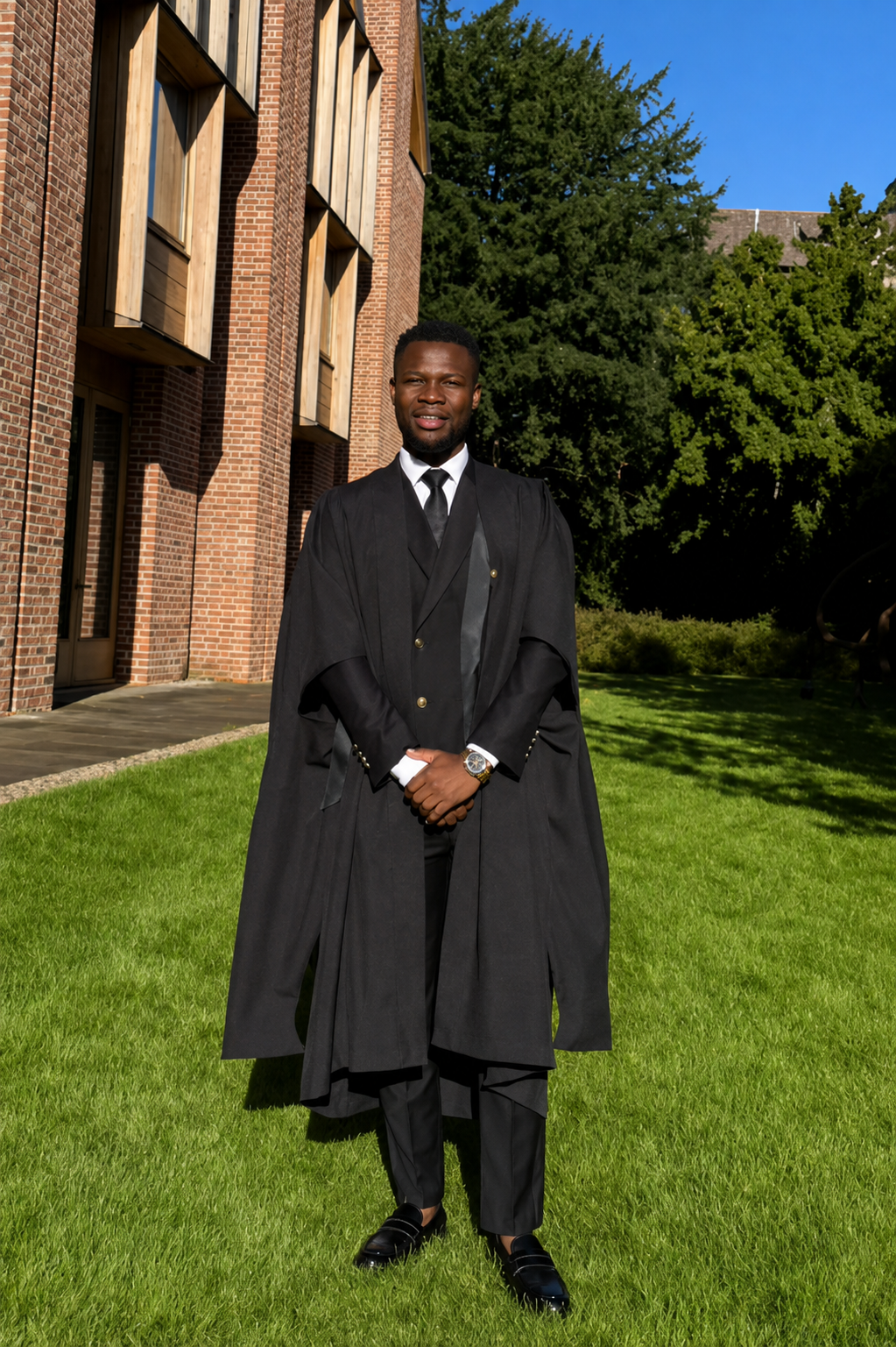 Abel Mavura in academic gown on a college lawn